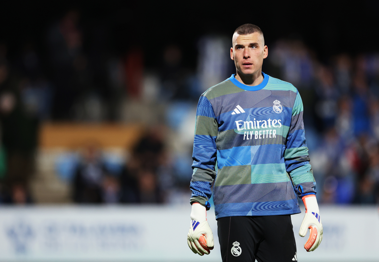 Real Madrid goalkeeper Andriy Lunin standing on the pitch during a match.