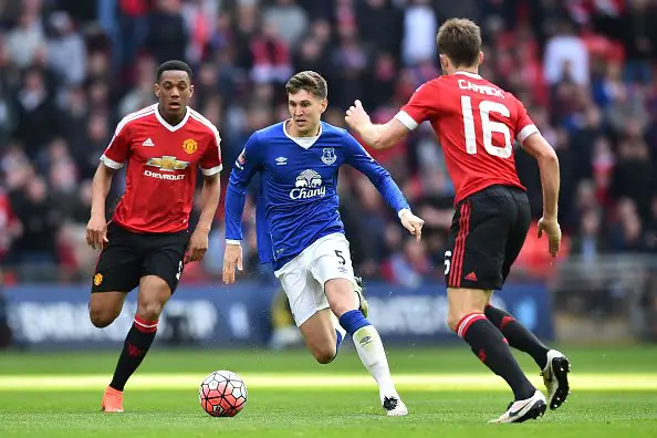 Everton's English defender John Stones (C) runs between Manchester United's French striker Anthony Martial (L) and Manchester United's English midfielder Michael Carrick (R) during the English FA Cup semi-final football match between Everton and Manchester United at Wembley Stadium in London on April 23, 2016. / AFP / BEN STANSALL / NOT FOR MARKETING OR ADVERTISING USE / RESTRICTED TO EDITORIAL USE        (Photo credit should read BEN STANSALL/AFP/Getty Images)