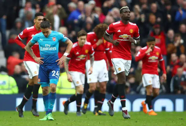 MANCHESTER, ENGLAND - APRIL 29:  Hector Bellerin of Arsenal looks dejected as Paul Pogba of Manchester United runs back to the half way line after his side score their second goal during the Premier League match between Manchester United and Arsenal at Old Trafford on April 29, 2018 in Manchester, England.  (Photo by Clive Brunskill/Getty Images)