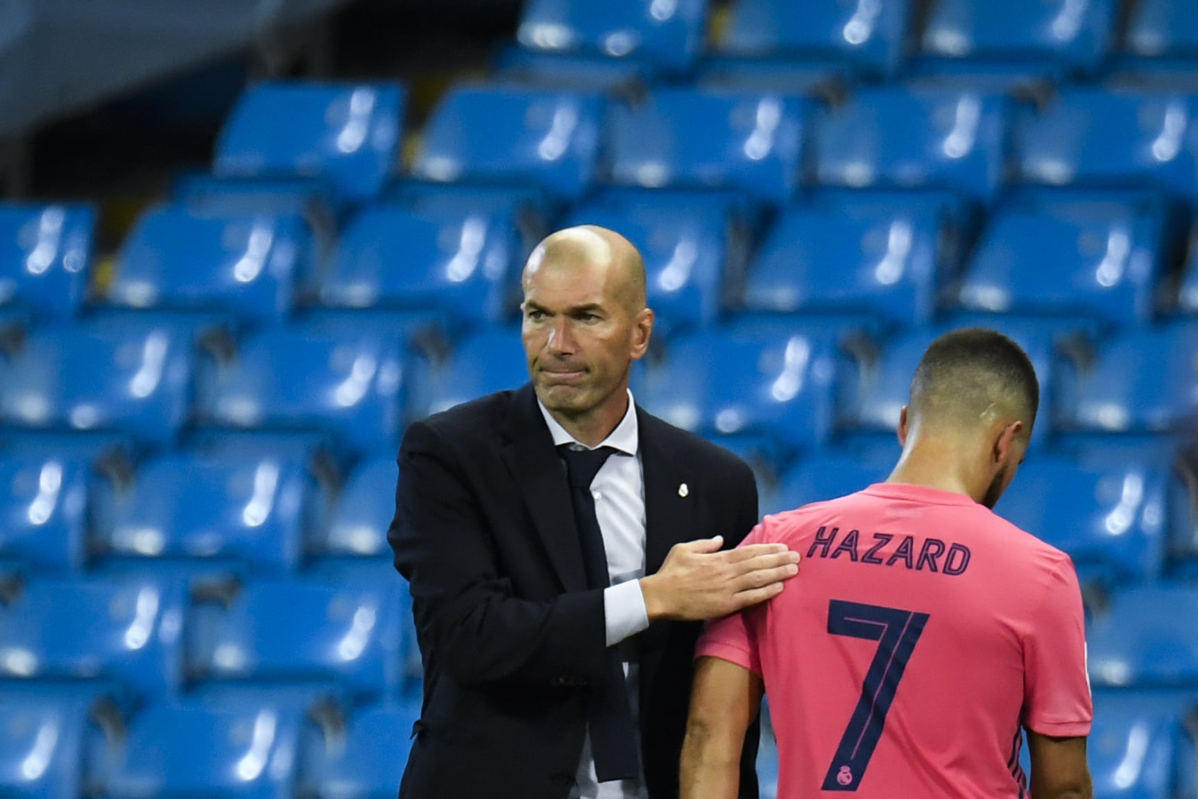 Real Madrid's French coach Zinedine Zidane (L) taps Real Madrid's Belgian forward Eden Hazard as he leaves the pitch after being substituted off during the UEFA Champions League round of 16 second leg football match between Manchester City and Real Madrid at the Etihad Stadium in Manchester, north west England on August 7, 2020. (Photo by PETER POWELL / POOL / AFP) (Photo by PETER POWELL/POOL/AFP via Getty Images)