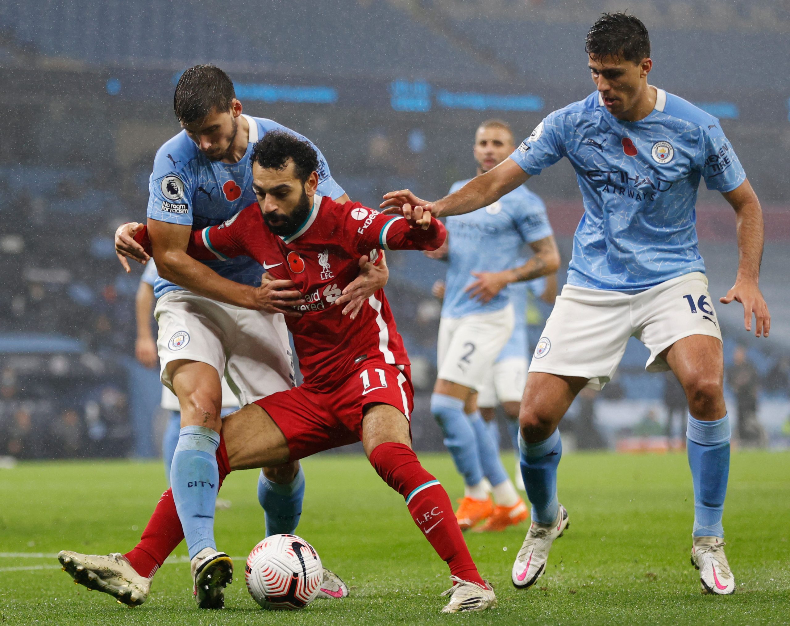Liverpool's Egyptian midfielder Mohamed Salah (C) battles with Manchester City's Portuguese defender Ruben Dias (L) and Manchester City's Spanish midfielder Rodri (R) during the English Premier League football match between Manchester City and Liverpool at the Etihad Stadium in Manchester, north west England, on November 8, 2020. (Photo by Clive Brunskill / POOL / AFP) / RESTRICTED TO EDITORIAL USE. No use with unauthorized audio, video, data, fixture lists, club/league logos or 'live' services. Online in-match use limited to 120 images. An additional 40 images may be used in extra time. No video emulation. Social media in-match use limited to 120 images. An additional 40 images may be used in extra time. No use in betting publications, games or single club/league/player publications. /  (Photo by CLIVE BRUNSKILL/POOL/AFP via Getty Images)