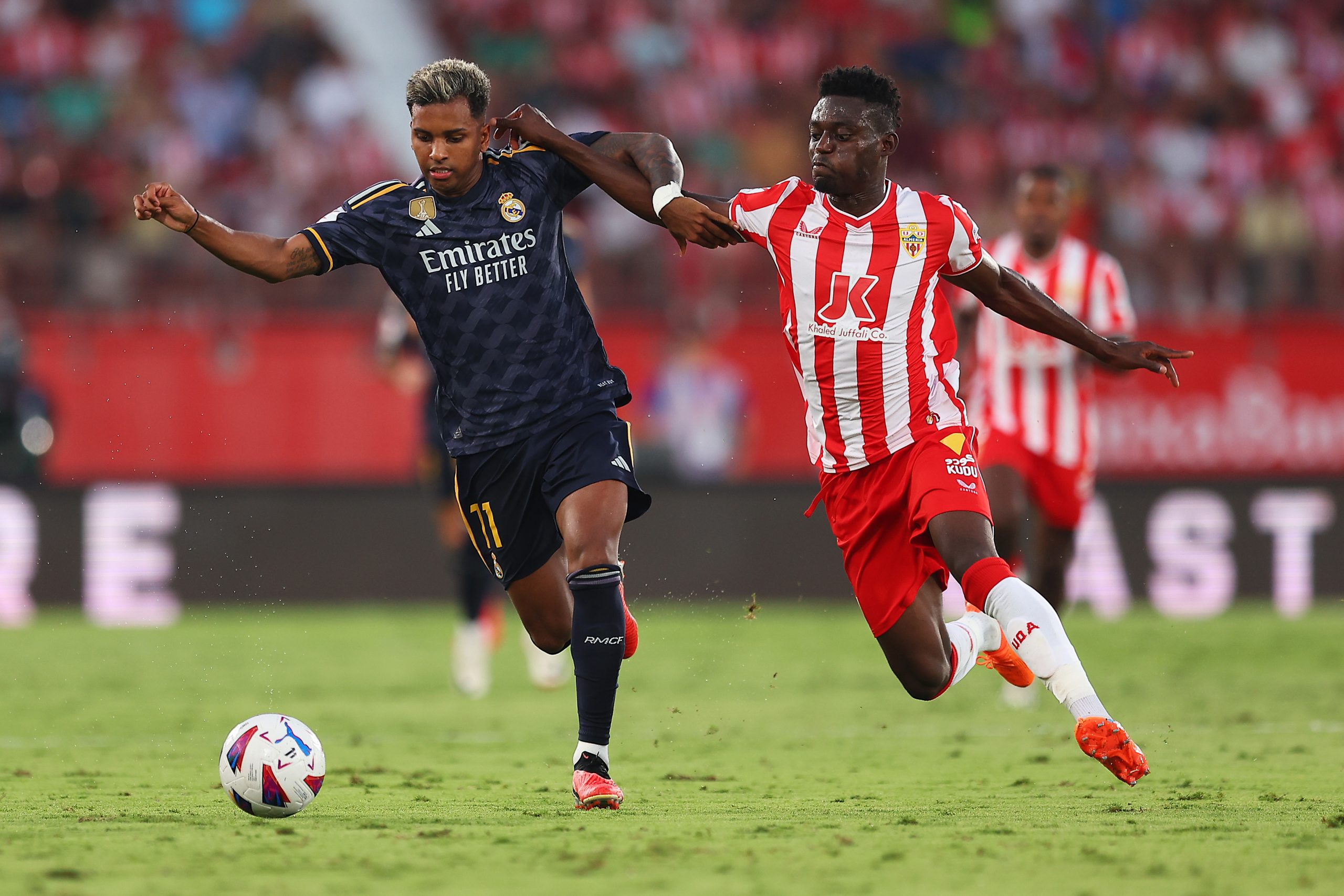 ALMERIA, SPAIN - AUGUST 19: Rodrygo of Real Madrid battles for possession with Iddrisu Baba of UD Almeria during the LaLiga EA Sports match between UD Almeria and Real Madrid CF at Juegos Mediterraneos on August 19, 2023 in Almeria, Spain. (Photo by Fran Santiago/Getty Images)