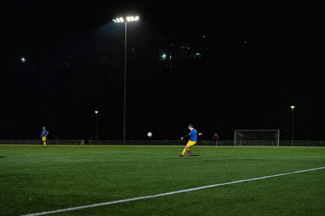 Fan of A-League kicking a football in a field at night