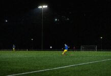 Use of Wearable A-League Tech by Fans and Its Positive Effect Fan of A-League kicking a football in a field at night