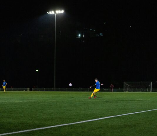 Fan of A-League kicking a football in a field at night