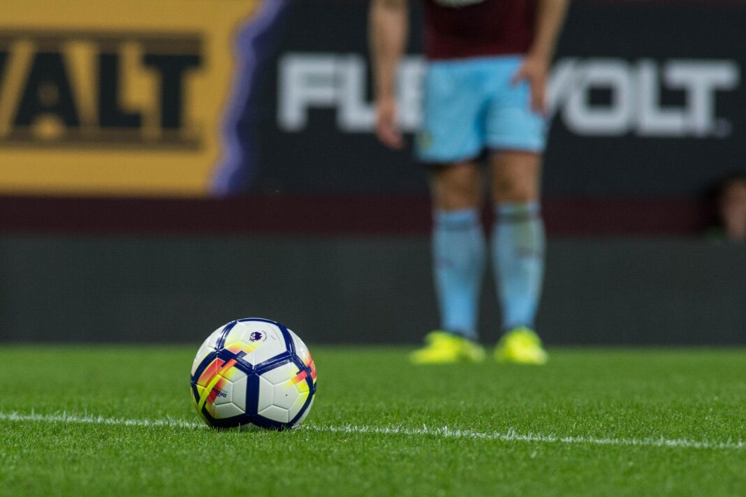 A Premier League lining up a football for a freekick.